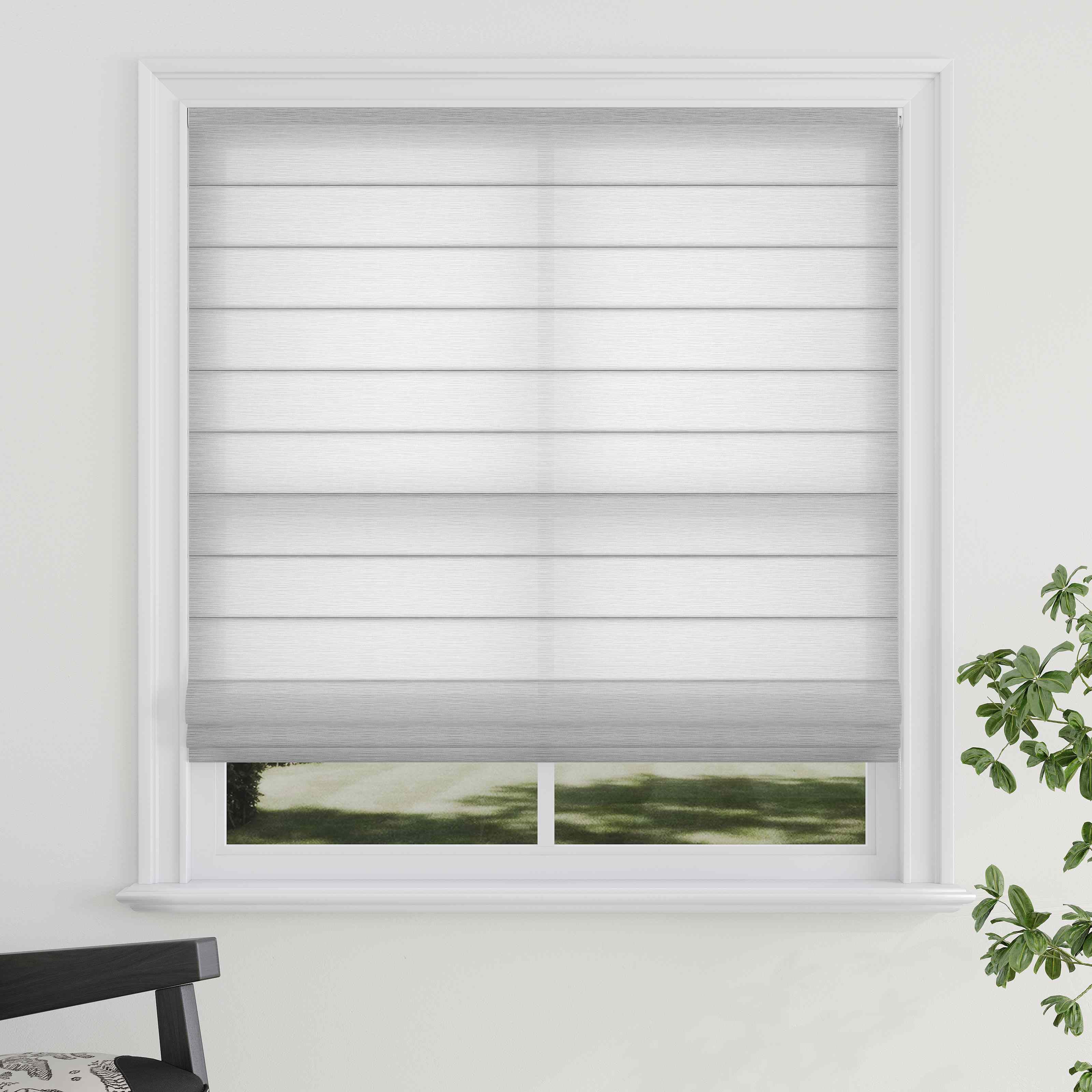 A grey Roman shade with a textured pattern, raised weave texture, installed in a window with a view of greenery outside. A chair with a striped pattern is partially visible to the left.